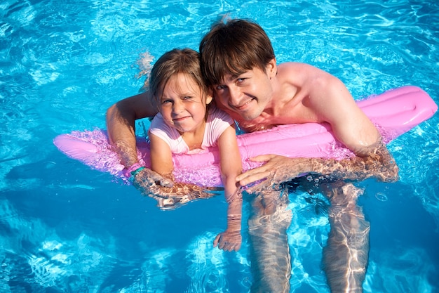 Zdjęcie tata i córka bawią się w basenie z różowym nadmuchiwanym