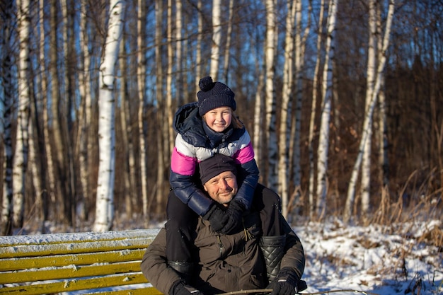 Tata i córka siedzą na ławce w zimowym parku