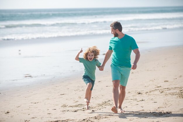 Tata i dziecko bawią się na świeżym powietrzu, ojciec i syn biegają na letniej plaży