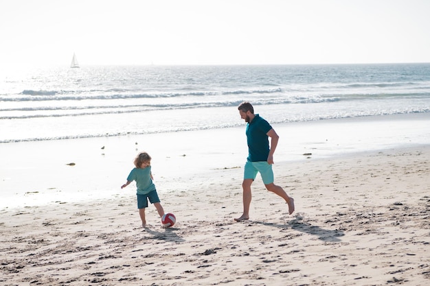 Tata i dziecko bawią się na świeżym powietrzu Ojciec i syn grają w piłkę nożną lub piłkę nożną na plaży podczas letnich rodzinnych wakacji Koncepcja dzieciństwa i rodzicielstwa