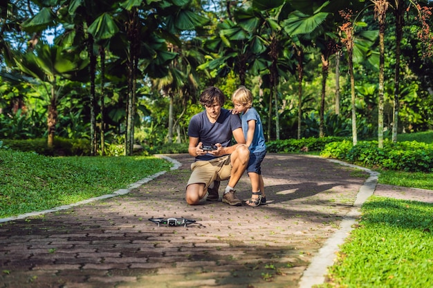 Tata i syn bawią się dronem Mężczyzna i chłopiec bawią się latającym dronem w słonecznym jesiennym ogrodzie szczęśliwy