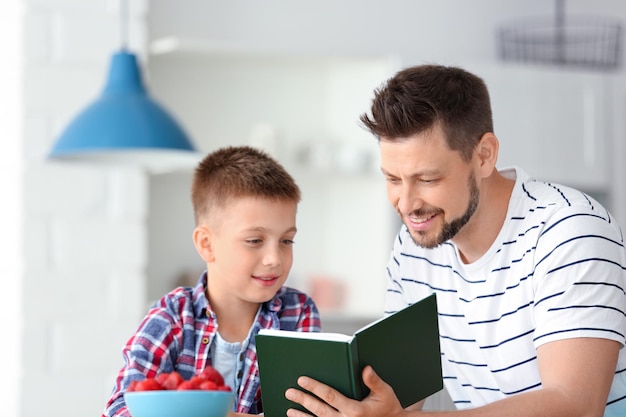 Tata i syn czytają ciekawą książkę w kuchni