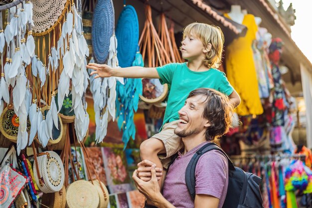 Tata i syn na targu w Ubud Bali Typowy sklep z pamiątkami sprzedający pamiątki i rękodzieła z Bali na słynnym targu Ubud Indonezja Targ balijski Pamiątki z drewna i rękodzieła miejscowych