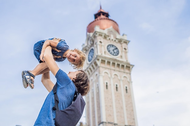 Tata i syn na tle budynku sułtana Abdula Samada w Kuala Lumpur, Malezja. Podróżowanie z koncepcją dzieci