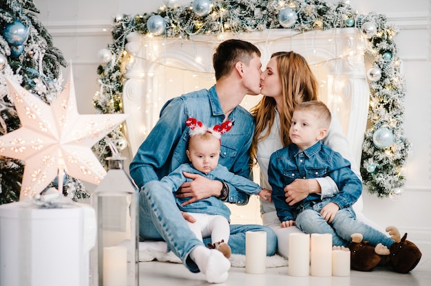 Tata, mama przytulają synka i córkę przy choince. Wesołych Świąt. Boże Narodzenie urządzone wnętrze. Pojęcie wakacji rodzinnych. Ścieśniać.