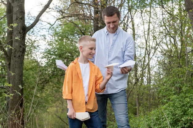 Tata pokazuje papierowy samolot szczęśliwemu synowi na świeżym powietrzu, spędzając razem czas