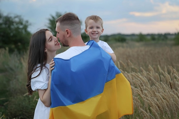 tata stoi plecami z flagą i przytula żonę i syna