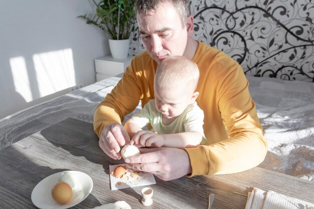 Tata świętuje Wielkanoc z małym synkiem Biją jajka, jedzą jajka i jedzą śniadanie Tata uczy dziecko