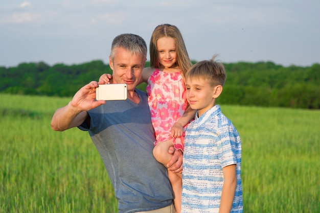 Tata z dziećmi robią selfie na telefonie.