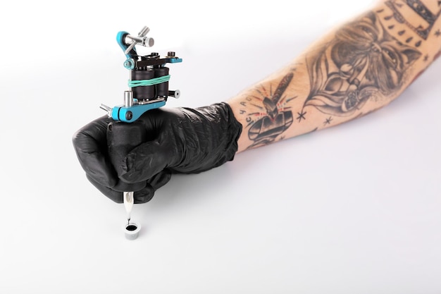 Tattooist ręka w czarnej rękawiczce z maszynką do tatuażu na białym tle z bliska