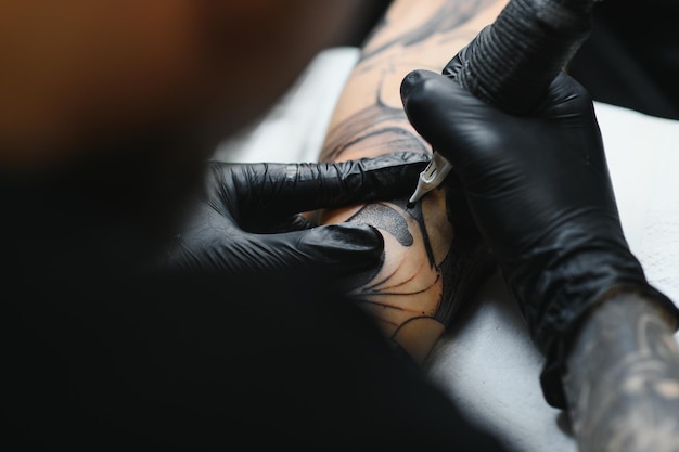 Tattooist ze swoim maszynowym tatuażem na ramieniu z narysowanym projektem, koncepcją sztuki i designu