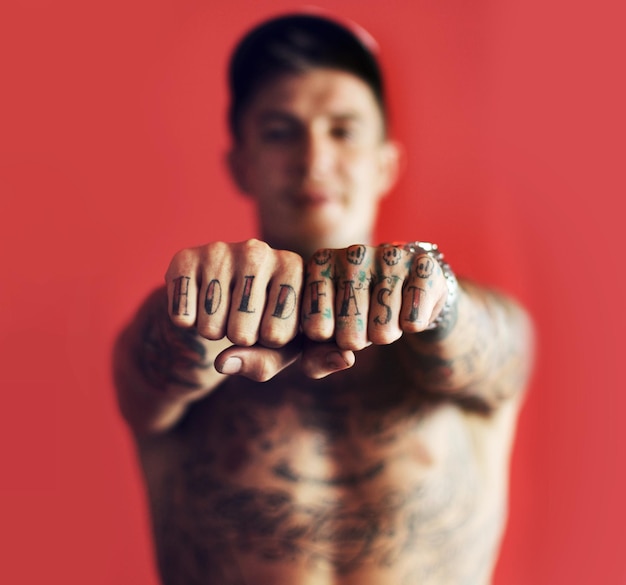 Tatuaż na pięści lub zamazany mężczyzna w studio na białym tle na czerwonym tle z wyjątkową, fajną lub artystyczną kreatywnością Zoom buntownika lub portret modnej osoby macho pokazującej ręce lub kostki tuszem lub tatuażami
