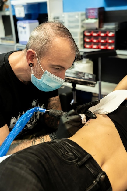 Tatuażysta koncentrujący się podczas pracy na skórze nierozpoznawalnej koncepcji kobiety pracy i koncentracji