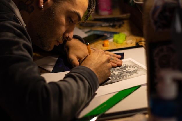 Tatuażysta patrzący na rysunek zaprojektowany na kartce papieru w studiu tatuażu.