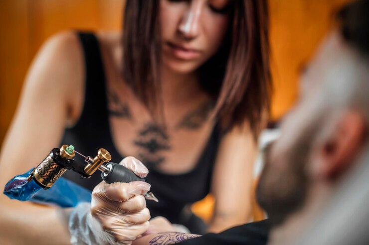 Tatuażysta tatuujący ramię mężczyzny w studio