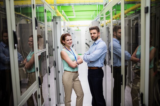 Technicy stojący z rękami skrzyżowanymi w serwerowni