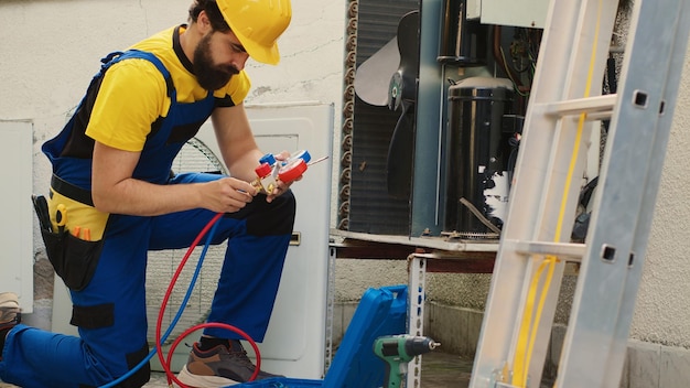 Technik ekspert zatrudniony do corocznej konserwacji klimatyzatora, montaż manometru przed rozpoczęciem pracy.