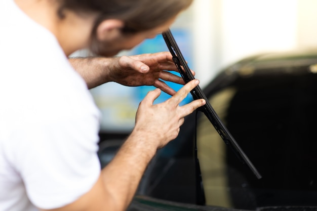 Technik i mechaniczna wymiana wycieraczek na stacji samochodowej. Konserwacji samochodów i koncepcji garażu auto serwis.