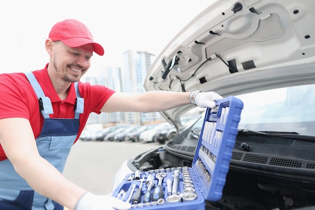 Technik motoryzacyjny uśmiechnięty i otwarty zestaw pełen sprzętu