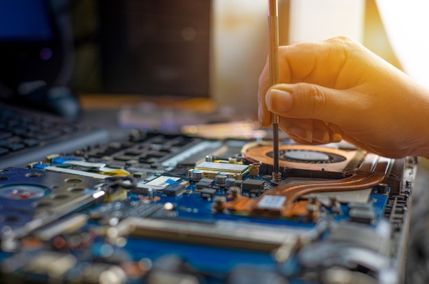 Technik naprawiający uszkodzony laptop notebook za pomocą śrubokręta