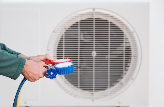 Technik serwisu klimatyzacji HVAC używający wskaźników do sprawdzania czynnika chłodniczego i dodawania czynnika chłodniczego