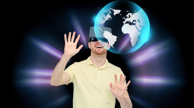 Zdjęcie technologia 3d, rzeczywistość wirtualna, cyberprzestrzeń, rozrywka i koncepcja ludzi - szczęśliwy człowiek z zestawem słuchawkowym rzeczywistości wirtualnej lub okularami 3d grający w grę i patrzący na projekcję globu na czarnym tle