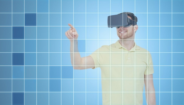 Zdjęcie technologia 3d, rzeczywistość wirtualna, rozrywka i koncepcja ludzi - szczęśliwy młody człowiek z zestawem słuchawkowym rzeczywistości wirtualnej lub okularami 3d grający w grę na niebieskim tle siatki