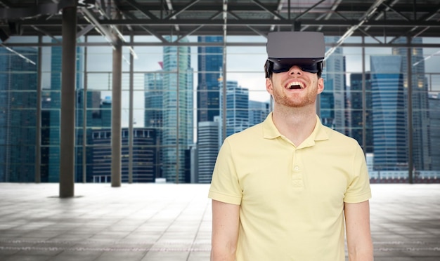 Technologia 3d, rzeczywistość wirtualna, rozrywka i koncepcja ludzi - szczęśliwy młody człowiek z zestawem słuchawkowym rzeczywistości wirtualnej lub okularami 3d grający w grę na przemysłowym pustym pokoju i tle panoramy miasta