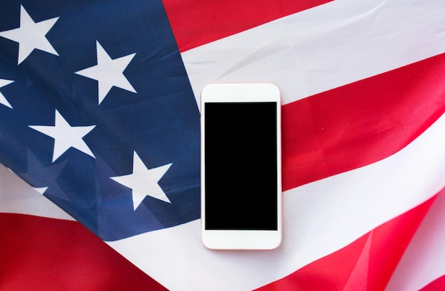 technologia, amerykański dzień niepodległości, koncepcja patriotyzmu i nacjonalizmu - zbliżenie smartfona z czarnym pustym ekranem na amerykańskiej fladze