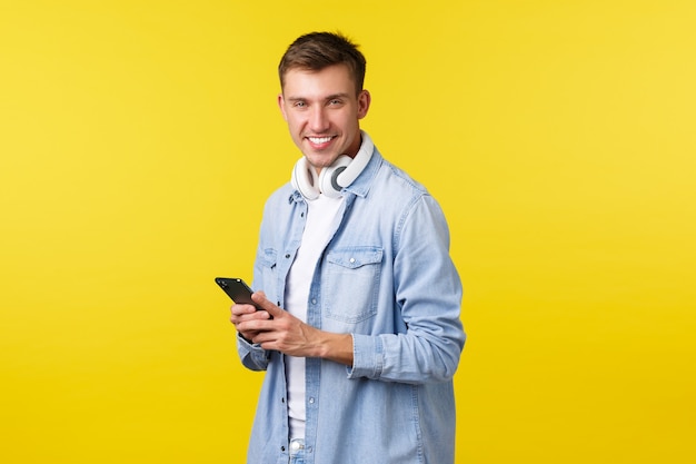 Technologia rekreacyjna i koncepcja reklamy aplikacji przystojny facet uśmiechający się jak przy użyciu telefonu komórkowego ...