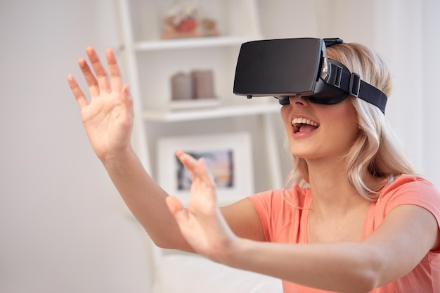 technologia, wirtualna rzeczywistość, rozrywka i koncepcja ludzi - szczęśliwa młoda kobieta z zestawem słuchawkowym do rzeczywistości wirtualnej lub okularami 3d grająca w grę w domu i dotykająca czegoś niewidzialnego