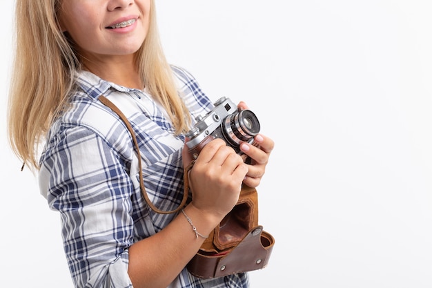 Technologie, fotografowanie i koncepcja ludzi - blondynka młoda kobieta z aparatem retro uśmiechając się nad białą powierzchnią