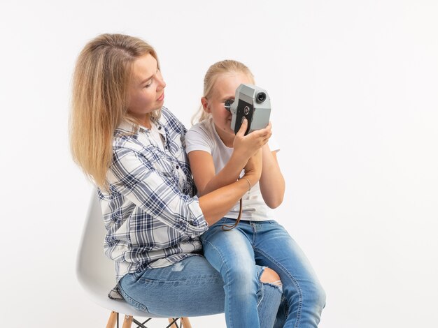 Technologie, fotografowanie i koncepcja rodziny - matka i córka za pomocą aparatu retro na białym tle.