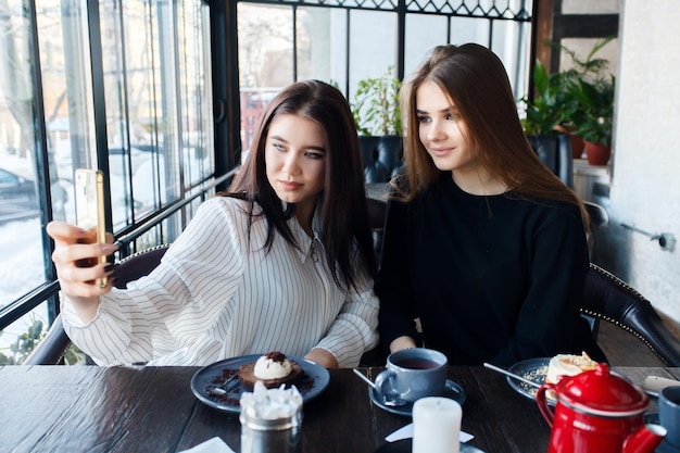 Technologie styl życia jedzenie ludzie nastolatki i koncepcja kawy Dwie młode kobiety biorące selfie za pomocą smartfona w centrum miasta Pojęcie szczęścia o ludziach i technologii