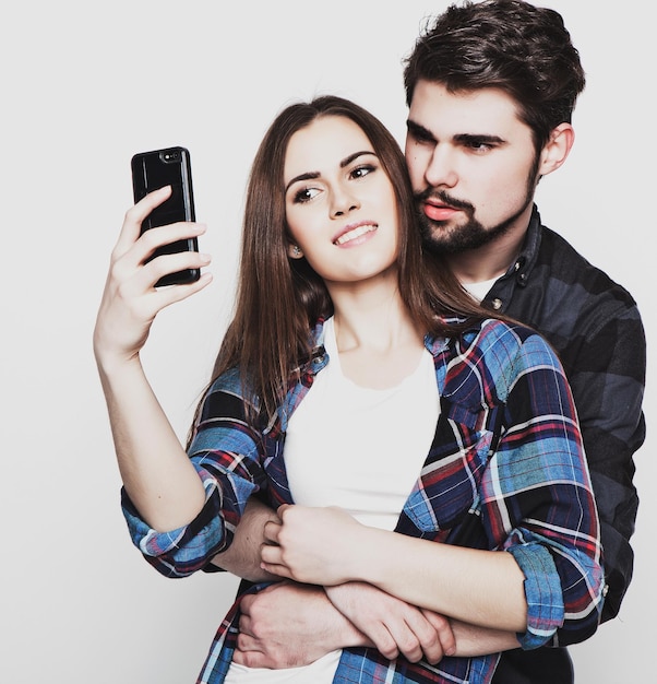 Technology internet emocjonalny i ludzi koncepcja uchwytywanie szczęśliwych chwil razem Szczęśliwa młoda kochająca się para robiąca selfie i uśmiechająca się stojąc na białym tle