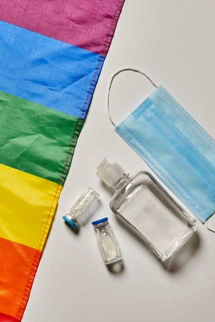 Tęczowa flaga Lgbt i covid artykuły higieny osobistej maska na twarz szczepionki przeciwko koronawirusowi i butelka dis ...
