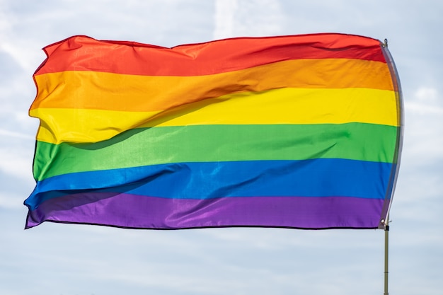 Zdjęcie tęczowa flaga ruch lgbt na słonecznym tle błękitnego nieba kolorowa flaga gejów macha