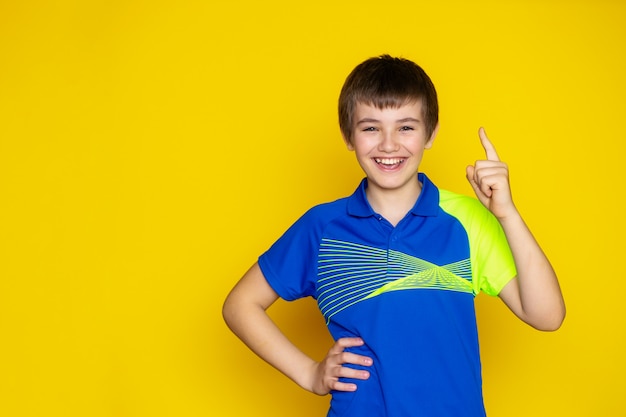 Teen chłopiec 11-12 lat w odzieży sportowej na żółtej ścianie.
