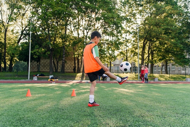 Teen chłopiec gry w piłkę nożną na boisku