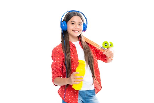 Teen dziewczyna 12 13 14 lat z deskorolką i słuchawkami na białym tle studio Fajny nowoczesny nastolatek w stylowych ubraniach Nastolatki styl życia dorywcza kultura młodzieżowa