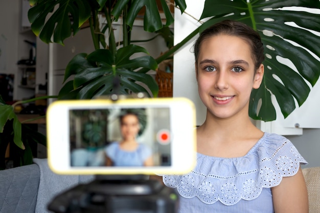 Zdjęcie teen dziewczyna blogger influencer nagrywania wideo koncepcja bloga mówiącego patrząc na smartfona na statywie w domu. nastoletni vloger społecznościowy strzelający vlog, przesyłający podcast online na telefon komórkowy.