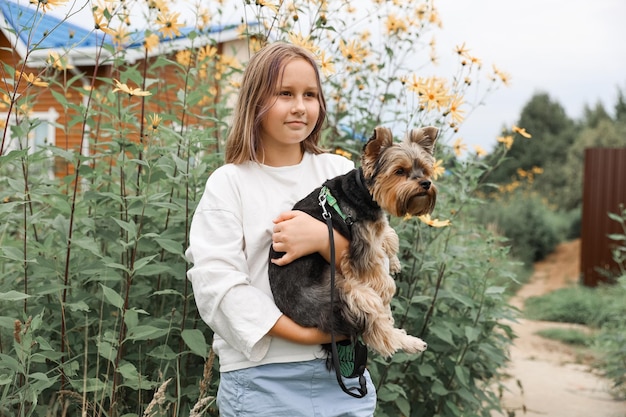 Teen dziewczyna na spacerze w letnim parku ze swoim zwierzakiem Yorkshire terrier. Dziecko wyprowadza psa