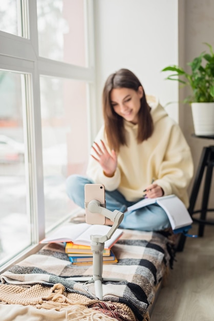 Teen school girl odległa szkoła lub studentka wirtualnego zdalnego e-learningu za pomocą aplikacji na telefon komórkowy w sypialni Zajęcia edukacyjne na odległość studiujące online w domu koncepcja Miękkie selektywne skupienie