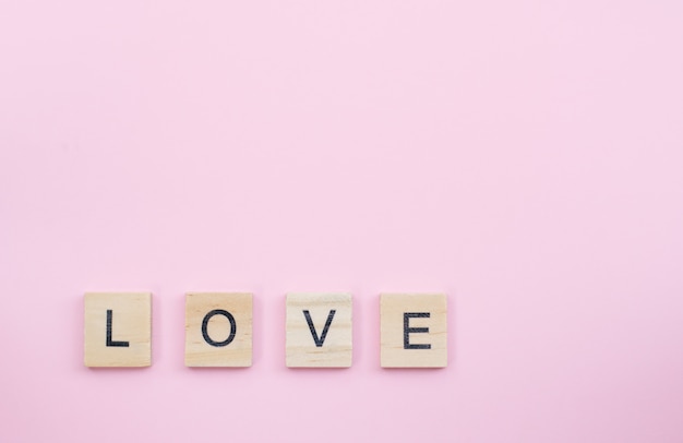 Tekst bloki drewniane pisowni miłości słowa na różowym tle