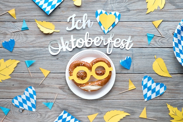 Tekst papierowy „Kocham Oktoberfest”, leżał płasko na rustykalnym drewnianym stole z zabawnym preclem