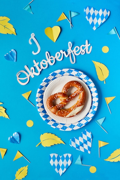 Tekst papierowy „Kocham Oktoberfest”, precel i pasujące dekoracje na niebieskim papierze