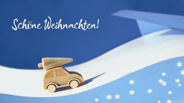 Tekst Schone Weihnachten Oznacza ładne święta W Języku Niemieckim Drewniana Zabawka Sylwetka Choinki Na Samochodziku Na Kolorowym Tle Papieru Warstwowego Xmas Wakacje Niebieskie Tło