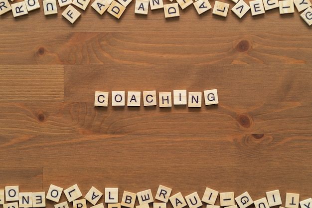Zdjęcie tekst słowa „coaching” napisany drewnianymi literami na drewnianym biurku