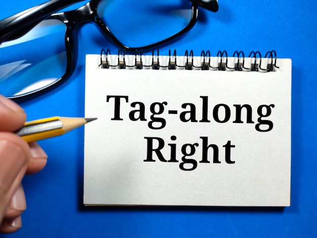 Tekst Tagalong Prawe pisanie na notebooku z ręką trzymającą ołówek i okulary na niebieskim tle