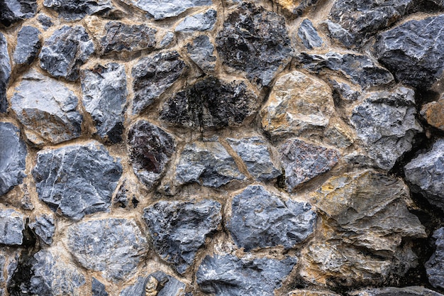 Tekstura ciemnej ściany murowanej Czarne kamienie i skały o różnym kształcie szarym tle